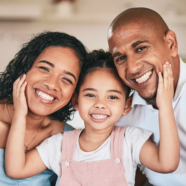 mother, father, and young daughter embracing and smiling