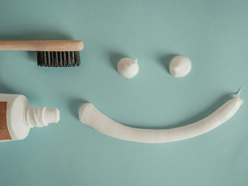 A tooth brush and tooth paste on a table and making a smile with a tooth paste